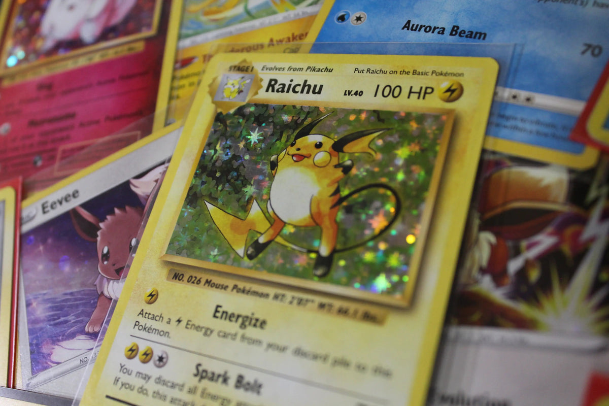 Holographic Raichu Pokémon card with Eevee and other collectible cards underneath