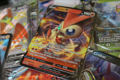 Close-up of Pokémon trading cards from PTC Collectibles, featuring Victini V holo card