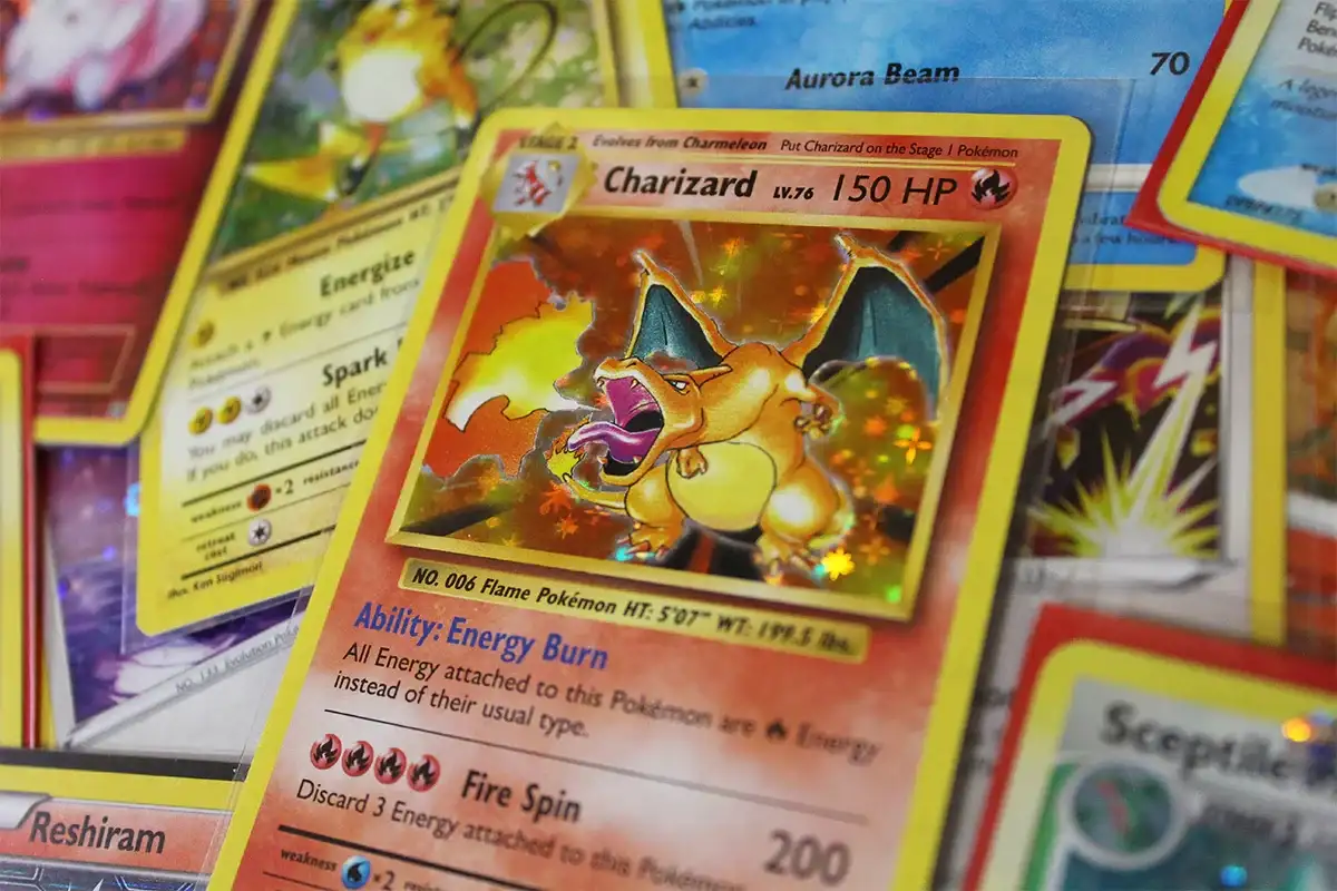 Close-up of rare holographic Charizard Pokémon card with other collectible cards, PTC Collectibles